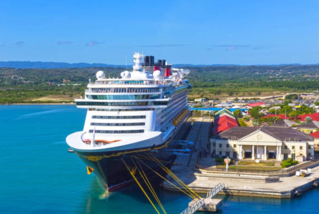Cruise ship moored at Historic Falmouth Pier Jamaica with port buildings and lush green coastline for cruise passenger arrival and shore excursions